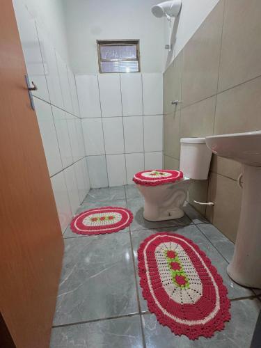 a bathroom with a toilet and two rugs on the floor at Casa Grande e Climatizada in Campo Grande