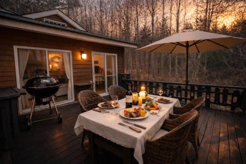 a table with food and a grill on a deck at karuizawa villa Baum in miyota in Miyota