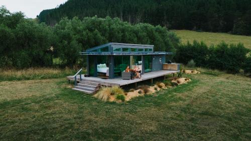 a house in a field with people sitting in it at Kokomea PurePod in Te Horo