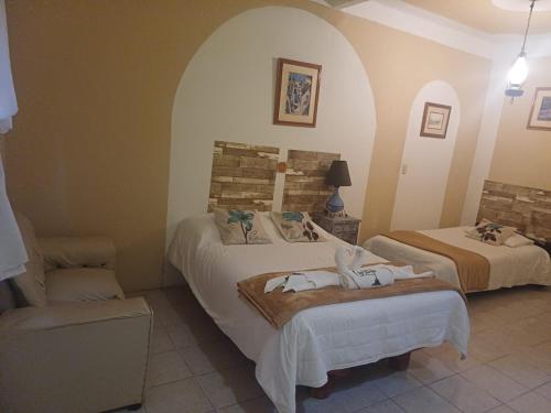 a hotel room with two beds and a chair at Hotel Los Faroles, Villa del Carbón in Villa del Carbón