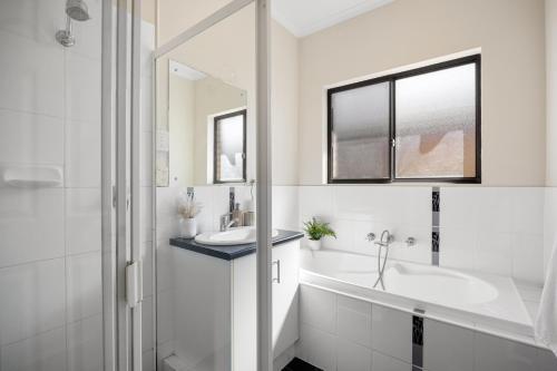a white bathroom with a sink and a mirror at Gone Coastal - Family Beachside Breeze in Grange