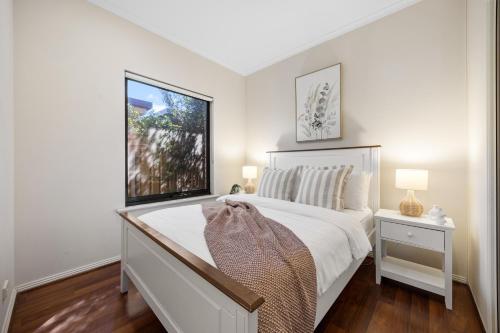 a white bedroom with a bed and a window at Gone Coastal - Family Beachside Breeze in Grange