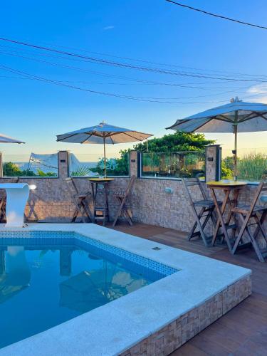 a swimming pool with tables and umbrellas on a patio at Pousada & Espaço Orlla 39 in Maricá