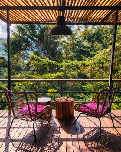 two chairs and a table on a porch with a view at Omghat Glamping - Domo Ganesha in El Peñol