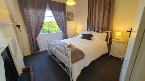 a bedroom with a white bed and a window at Haven Cottage Kangaroo Island in Kingscote