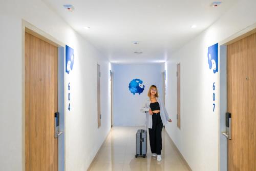 a woman walking down a hallway with a suitcase at Kokotel Chiang Mai Nimman in Chiang Mai