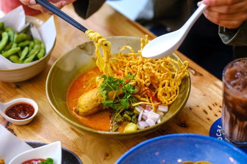 a plate of food with noodles in a bowl on a table at Kokotel Chiang Mai Nimman in Chiang Mai