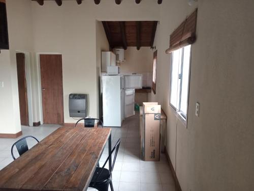 a kitchen with a wooden table and a refrigerator at Posada del Río 2 in Ciudad Lujan de Cuyo