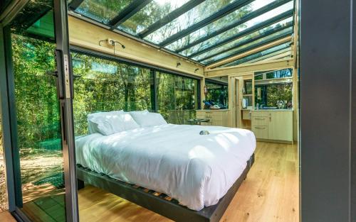 a bedroom with a bed in a glass house at Mākoha PurePod in Kerikeri