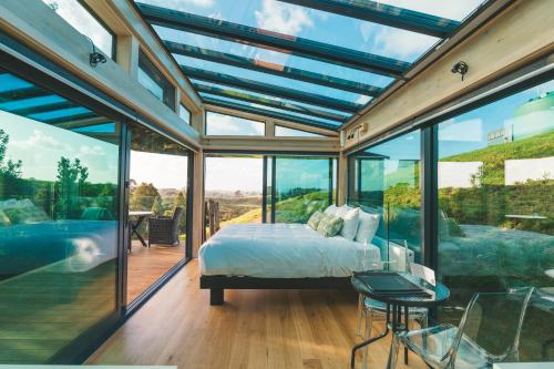 a bedroom with a bed and large glass windows at Rewarewa PurePod in Helensville