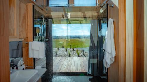a bathroom with a shower with a view of a garden at Matū PurePod - Waitomo in Otorohanga