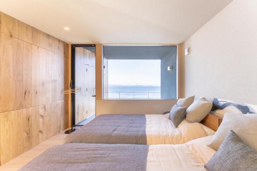 a bedroom with a bed and a large window at Villa CASK Setouchi in Mitoyo