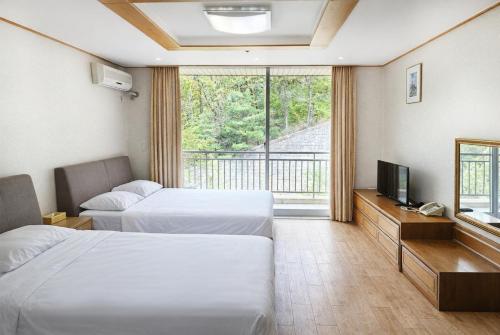 a hotel room with two beds and a television at Gyeongju Ilsung Condo in Gyeongju