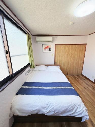 a large bed in a small room with windows at Uhome Haneda Apartment in Tokyo