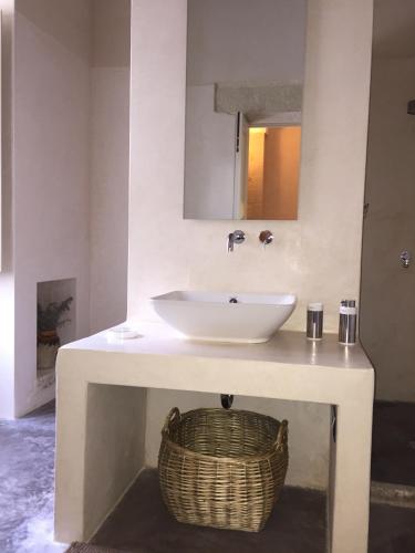 a bathroom with a sink and a basket at Antica Dimora Giardini Segreti in Giuggianello