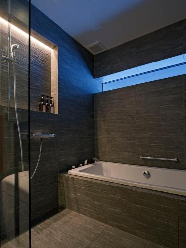a bathroom with a tub and a glass shower at TsuTsu Furano by H2 Life in Furano