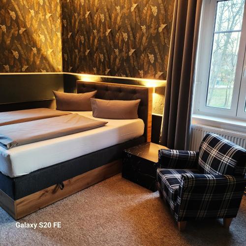 a bedroom with a bed and a chair in it at Parkhotel Schwedt in Schwedt