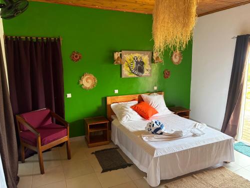 a green bedroom with a bed and a chair at Villa Baby lodge in Hell-Ville