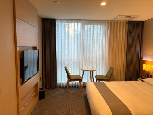a hotel room with a bed and a television and a table at 센텀스위트호텔 in Busan
