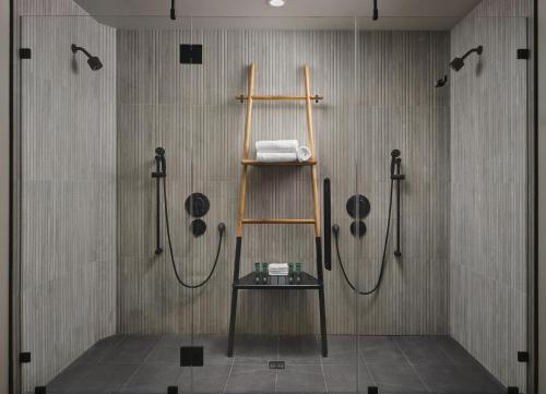 a bathroom with a shower and a shelf with shower heads at Alila Marea Beach Resort Encinitas, a Hyatt Resort in Encinitas