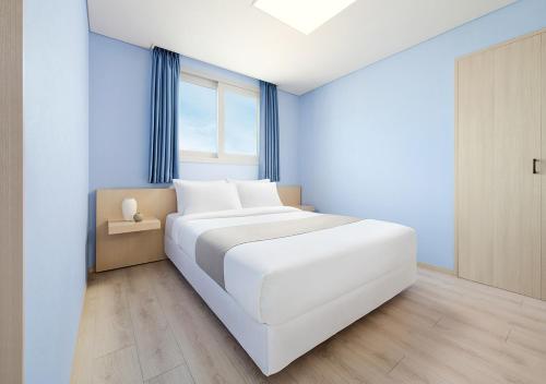 a white bed in a room with a window at Hanwha Resort Daecheon Paros in Boryeong
