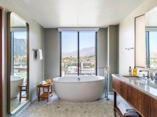 a bathroom with a tub and two sinks and a large window at Thompson Palm Springs, By Hyatt in Palm Springs