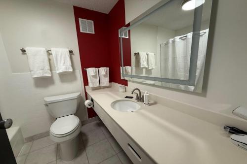 a bathroom with a toilet and a sink with a mirror at Ramada by Wyndham Cobleskill in Cobleskill