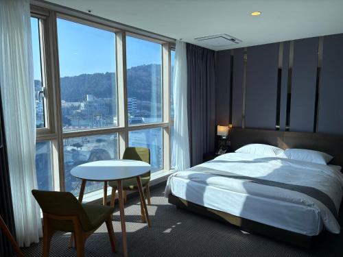 a hotel room with a bed and a table and windows at 센텀스위트호텔 in Busan