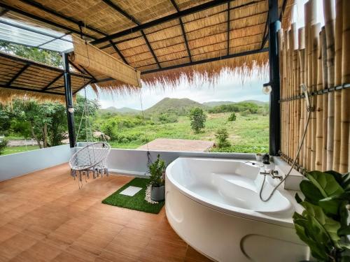 a bathroom with a tub and a large window at Mondara Villa and Glamping in Ban Bo Wi