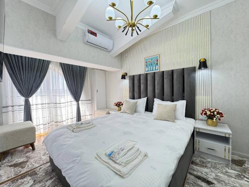 a bedroom with a large white bed and a chandelier at White House Apartment in Samarkand