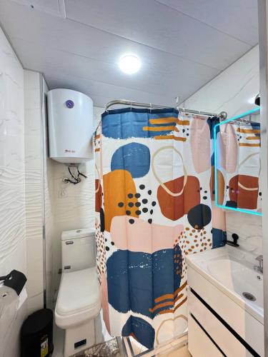 a bathroom with a toilet and a shower curtain at White House Apartment in Samarkand