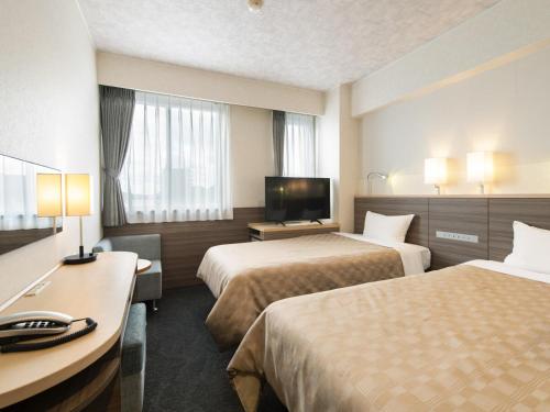 a hotel room with two beds and a flat screen tv at Onomichi Daiichi Hotel in Onomichi