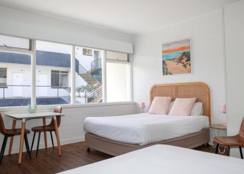 a bedroom with two beds and a table and chairs at Harbour View Motel in Robe