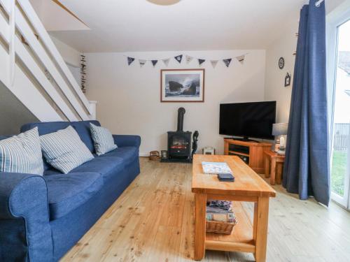 a living room with a blue couch and a tv at Bwthyn y Mor in Porthmadog
