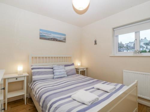 a bedroom with a bed and two tables and a window at Bwthyn y Mor in Porthmadog