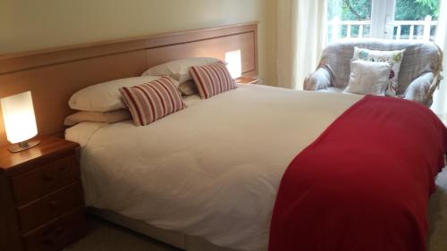 a bedroom with a large bed and a chair at Lakeland Midsummer Lakehouse in Oughterard