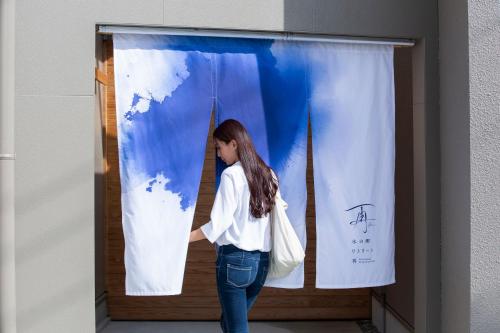 a woman is standing in front of a curtain at 水の郷リトリート 再 in Katori