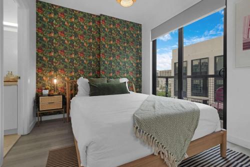 a bedroom with a large bed and a large window at Voy House Wynwood with Rooftop Pool in Miami