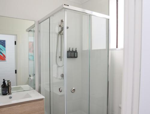 a white bathroom with a shower and a sink at Harbour View Motel in Robe