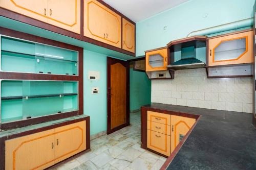 an empty kitchen with wooden cabinets and counters at Karthees Homestay in Rāmeswaram