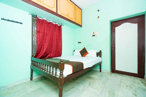 a bedroom with a bed with a red curtain at Karthees Homestay in Rāmeswaram