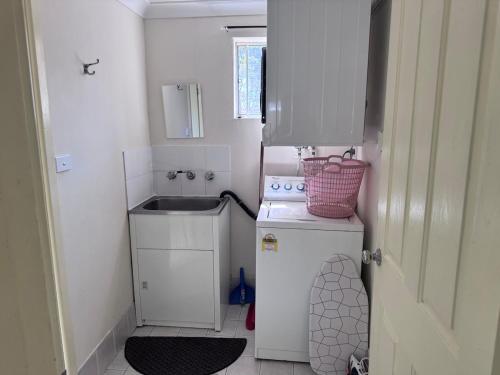 a small kitchen with a sink and a refrigerator at Toukley Lakeside Apartment in Toukley