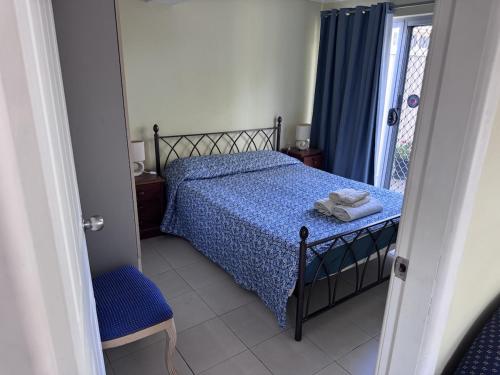 a bedroom with a bed with a blue comforter at Toukley Lakeside Apartment in Toukley