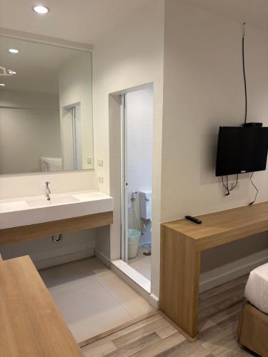 a bathroom with a sink and a mirror and a television at Nantra Hua Hin in Hua Hin