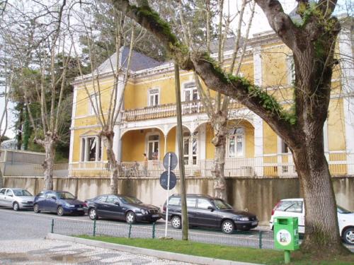 une maison jaune avec des voitures garées devant elle dans l'établissement Espaco Edla, à Sintra