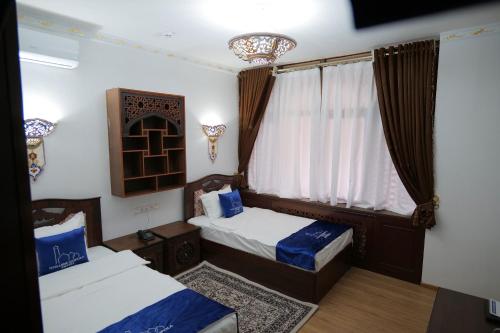 a bedroom with two beds and a window at Golubie Kupola Hotel 华人酒店 in Bukhara