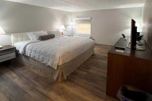 a bedroom with a bed and a desk and a television at Clarion Pointe South Portland in South Portland