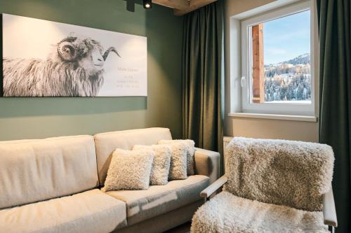 a living room with a couch and a picture of a sheep at Almresort Gartnerkofel Nassfeld in Sonnenalpe Nassfeld