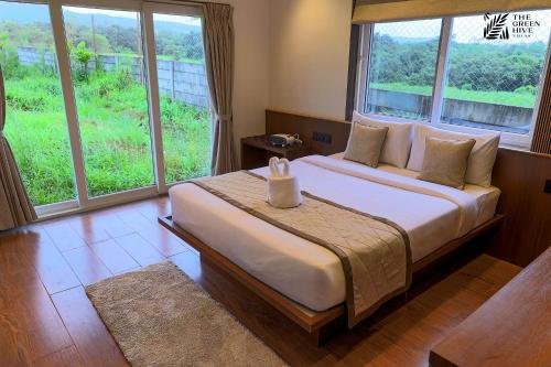 a bedroom with a large bed with a large window at The Green Hive Villas in Belgaum