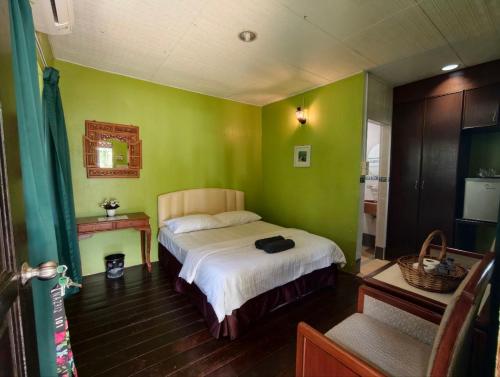 a bedroom with a bed in a room with green walls at Nazri's Place 2 in Tioman Island